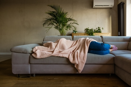 Young woman feeling cold under blanket.