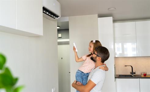 Family, father and child turn on air conditioner using remote control.